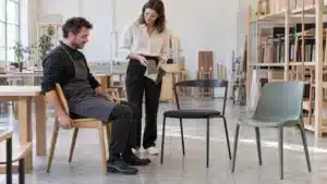 Illustration d’un professionnel testant une chaise avec une architecte devant trois assises différentes.